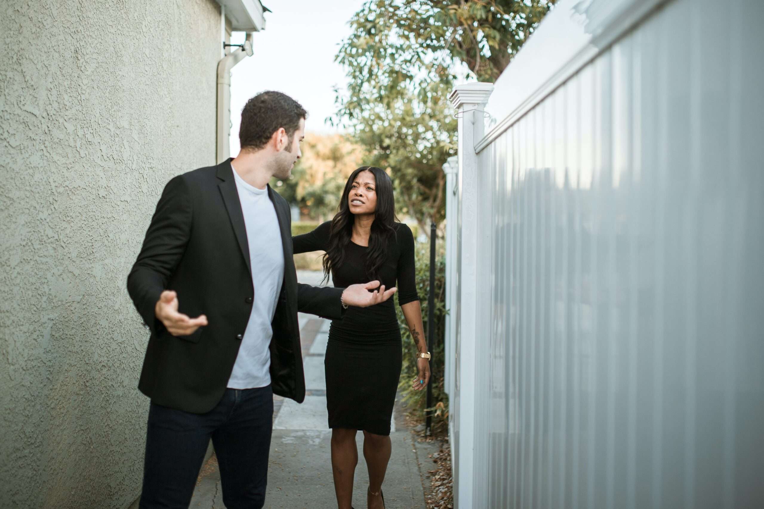 A man and a woman in a heated discussion outdoors, exemplifying a double standard in communication and emotional expression.